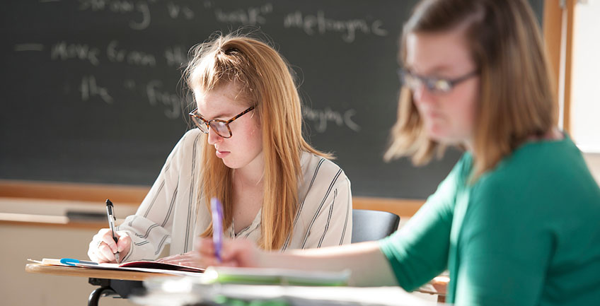 Two masters students writing in a classroom